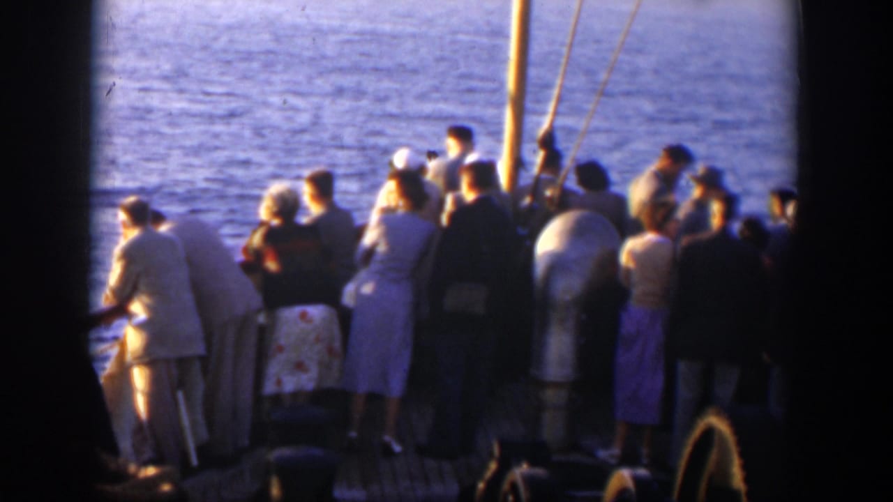 Crowd of passengers stands on deck near rigging and a large cylindrical fitting.