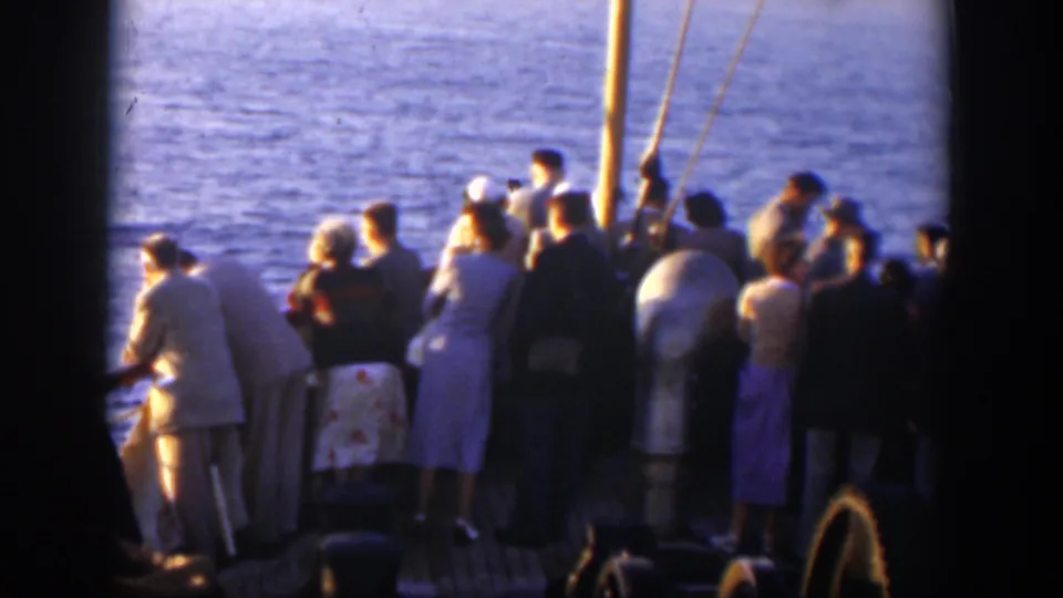 Passengers in mid-century clothing stand near rigging and deck equipment during a Cuba boat excursion.