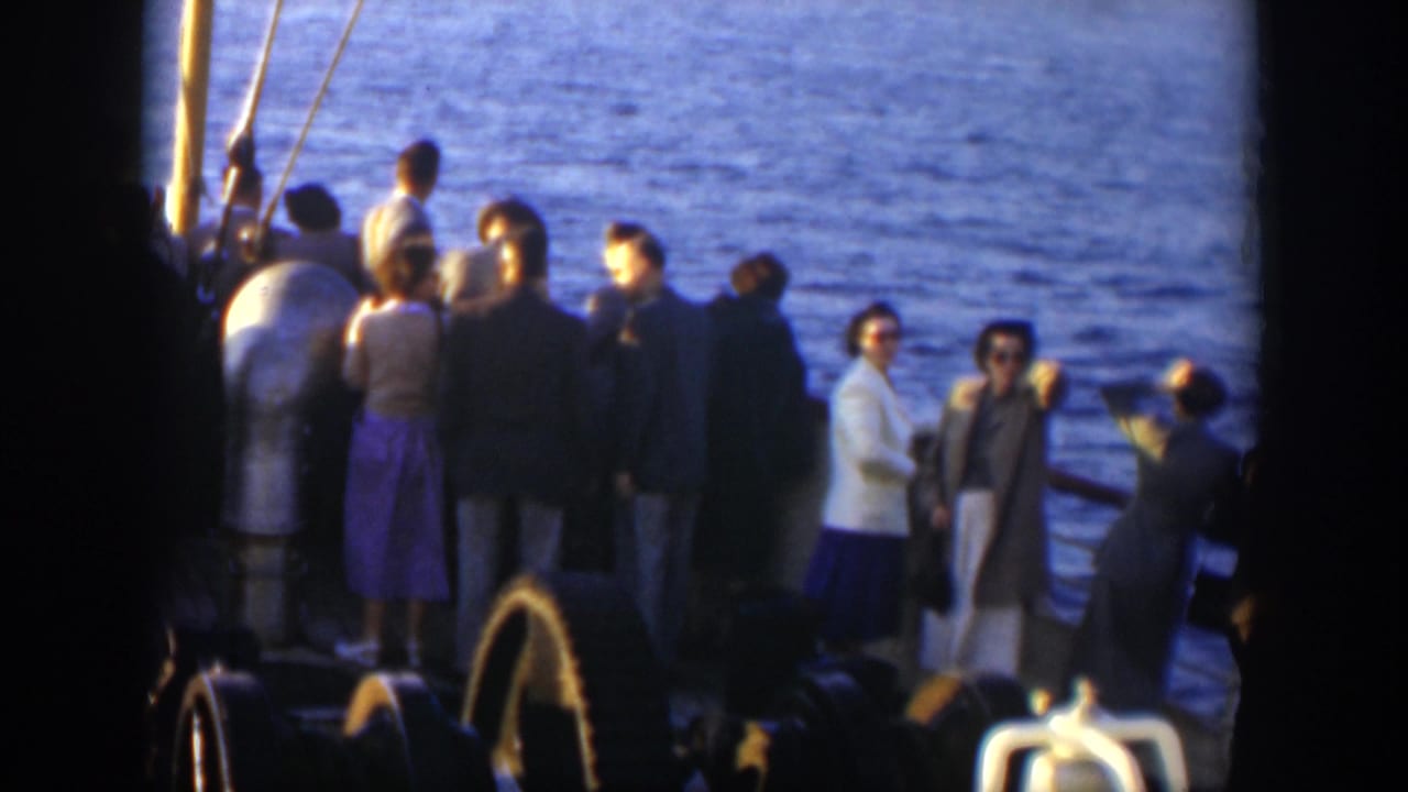 Adult passengers stand at a ship rail with open ocean behind them.