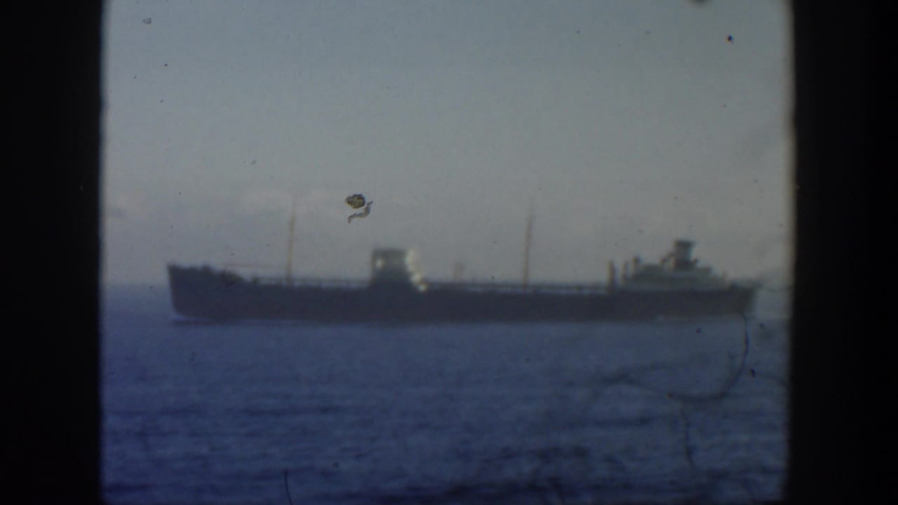 Long ship on the horizon with calm sea below and dark vertical frame edges around the view.