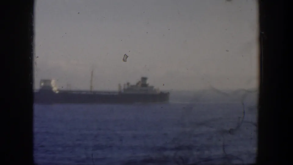 A distant ship on calm sea in 1951 Cuba-area 8mm footage, with soft focus and visible gate edges.
