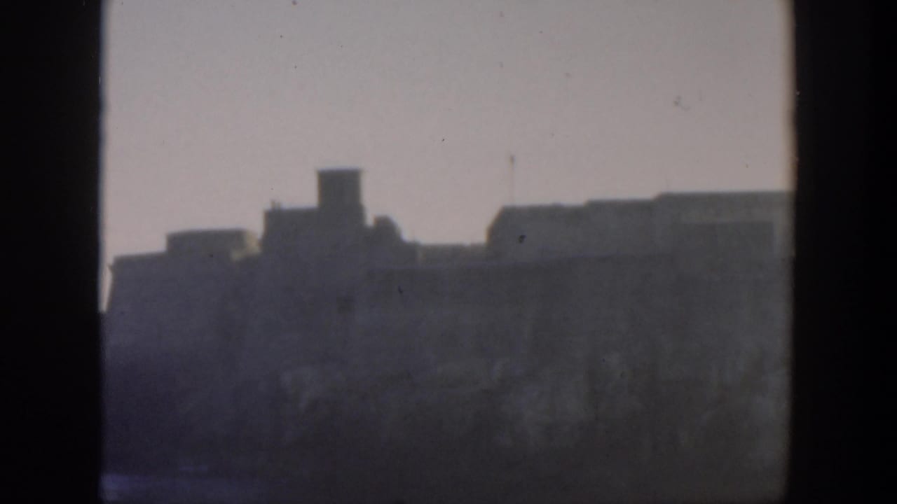 Distant hazy fortification seen through dark vertical framing.