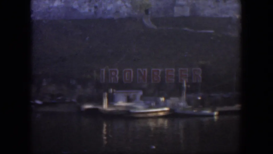 1951 Cuba waterfront view with a small white boat moored beneath large red Ironbeer letters on a dark hillside or wall.