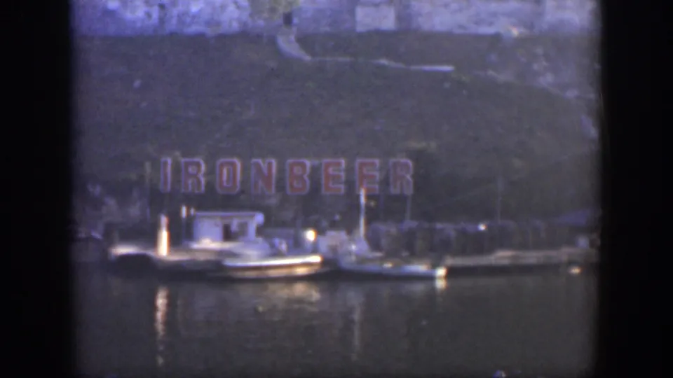 Color 8mm frame from Cuba in 1951 showing red Ironbeer lettering above small moored boats and reflective water.