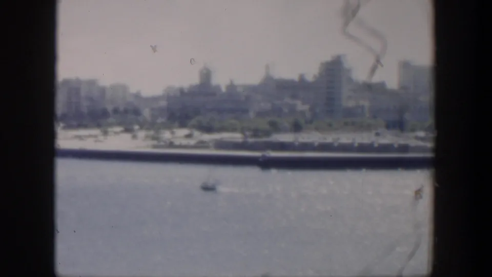 The final 1951 Cuba frame holds on harbor water, a small boat, and a distant urban shoreline softened by grain, fading, and handheld framing.