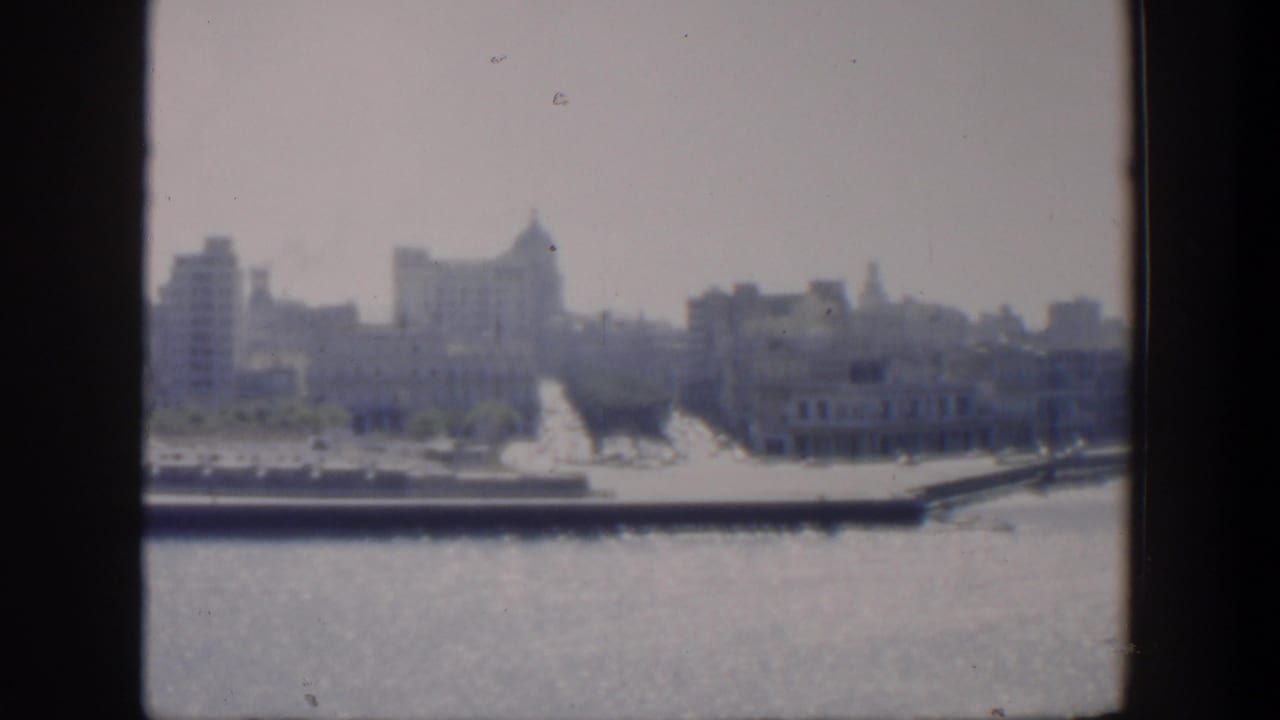 Distant coastal cityscape across water with buildings and a waterfront edge.