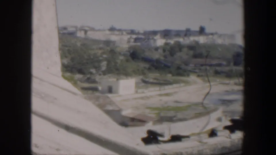 1951 Cuba frame from an elevated angle showing concrete structure, landscaped greenery, roads, and distant shoreline buildings.