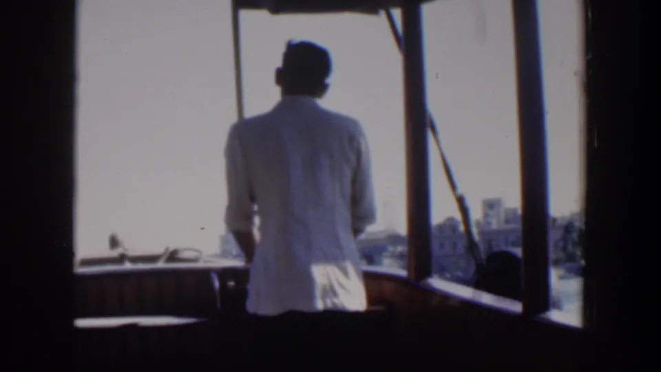 Soft 8mm frame from Cuba in 1951 with a man in white standing inside the boat as the waterfront passes ahead.