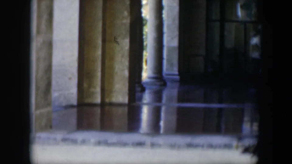 A dim Cuban building entrance shows stone columns, polished flooring and dark window openings in a soft 8mm frame.