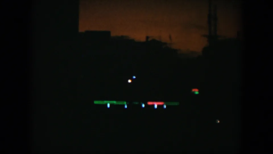 The final frame holds on a very dark skyline with low silhouettes and distant colored lights.