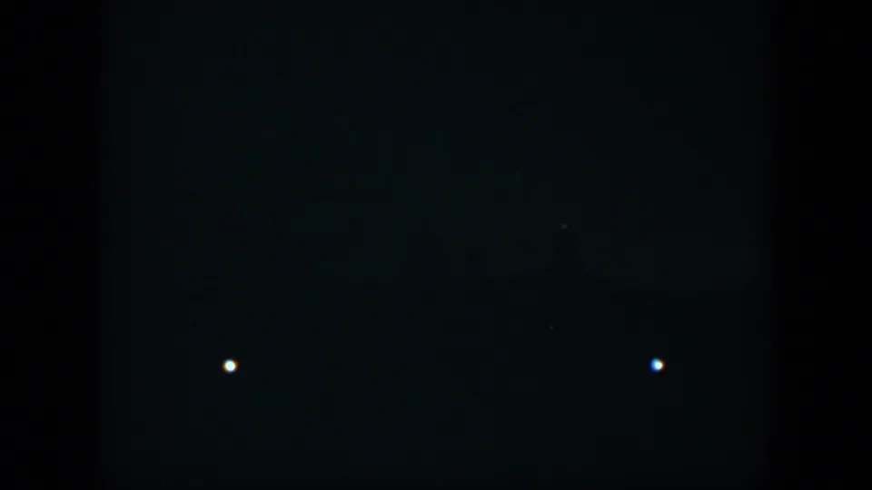 1951 Cuba 8mm frame showing a mostly black night scene with two isolated white lights and dim points near the bottom.