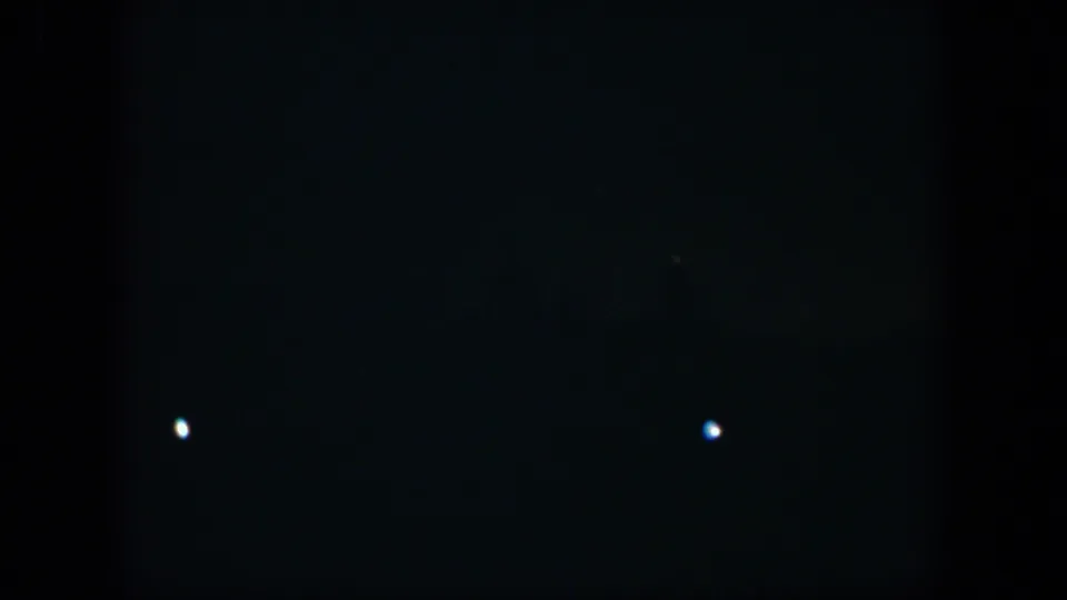 1951 Cuba 8mm frame with a single bright white point in darkness and scattered dim lights along the lower edge.