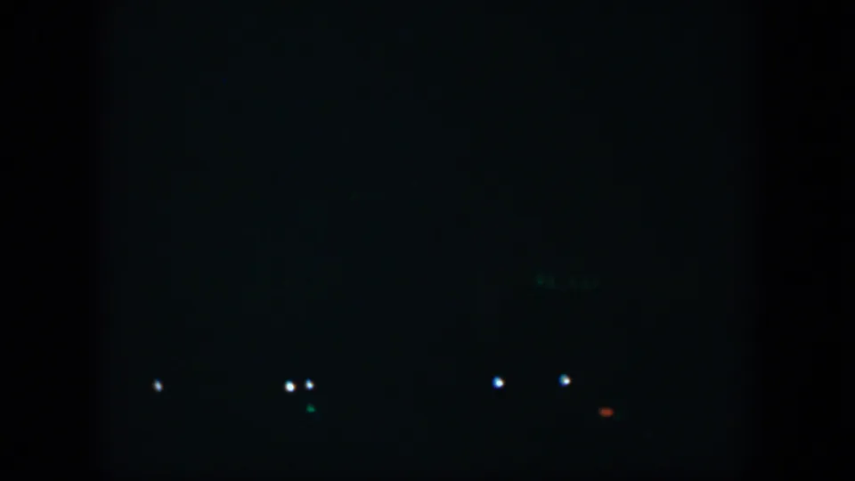 1951 Cuba 8mm frame showing small white points low in the frame with a faint red-orange light against darkness.