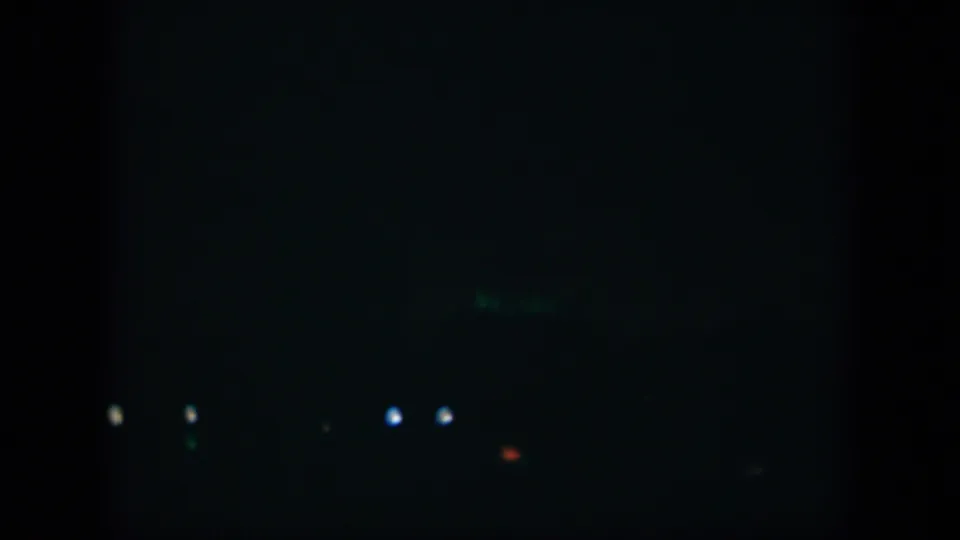 1951 Cuba 8mm frame showing a very dark exterior with isolated points of light and a faint green PARK sign in the distance.