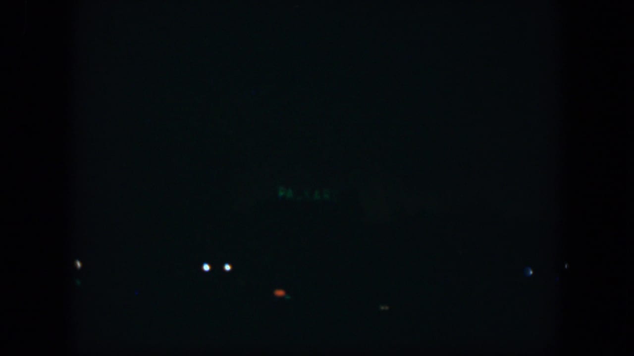 Dark urban night scene with a few small lights across the frame.