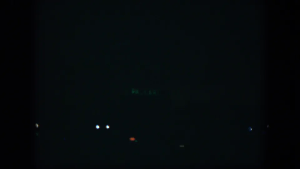 Low-light 8mm view from Cuba in 1951, with a mostly black frame, distant lights, and indistinct urban shapes.