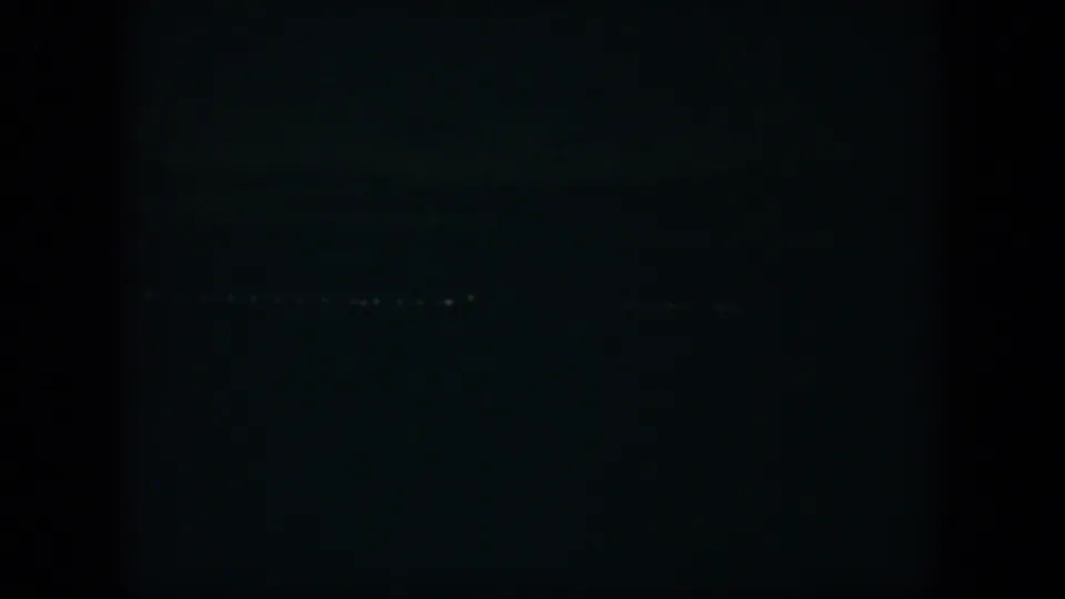 Low-light 8mm frame from Cuba in 1951 showing faint distant lights in darkness.