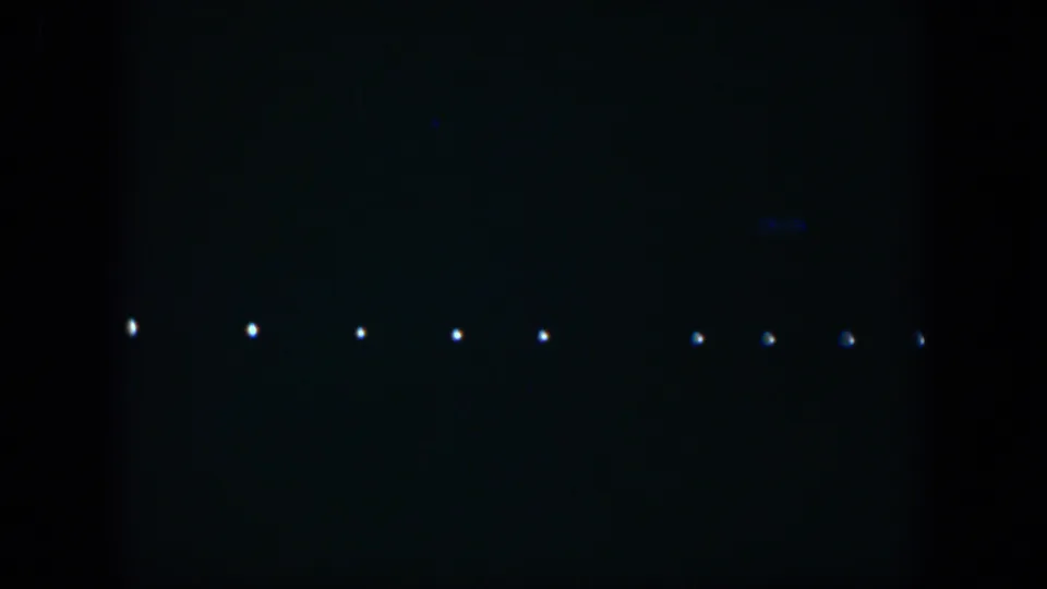 Low-light 1951 Cuba 8mm frame with distant spaced lights and faint color traces in darkness.