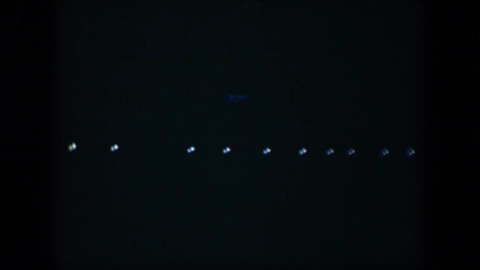 1951 Cuba 8mm frame showing dim rows of white lights low in a dark night-sky composition.