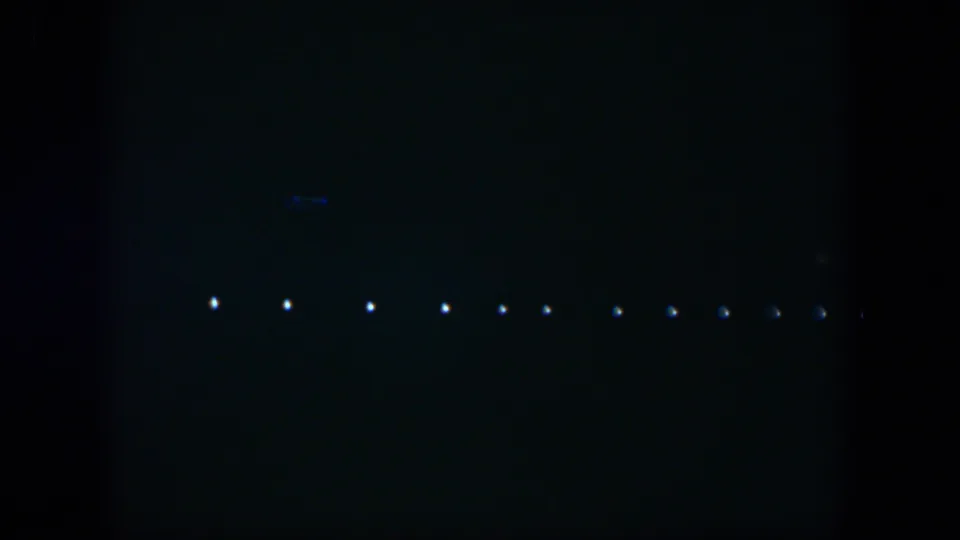 1951 Cuba 8mm frame with a row of white lights and faint blue marks in a very dark night view.