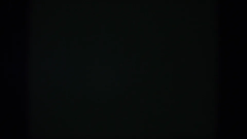 A mostly black 8mm frame with slight green tone and no clear subject visible, matching a brief dark passage in the reel.