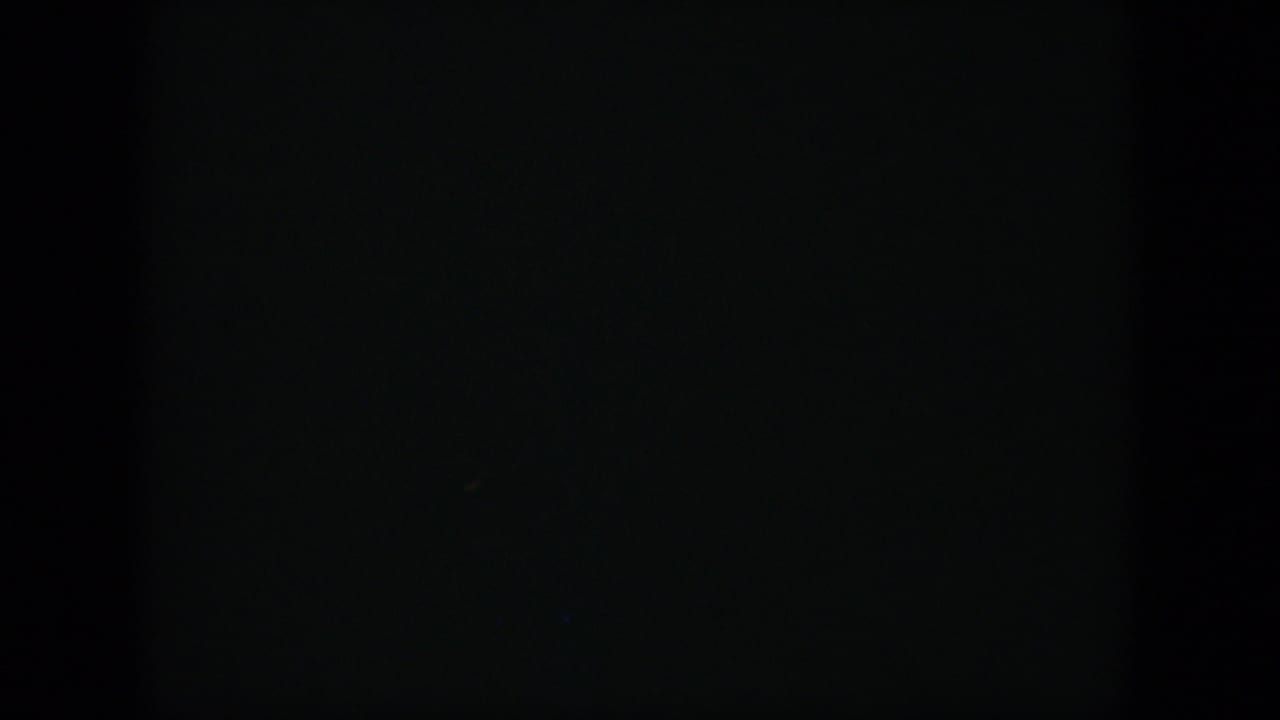 Mostly dark film frame with little visible detail.