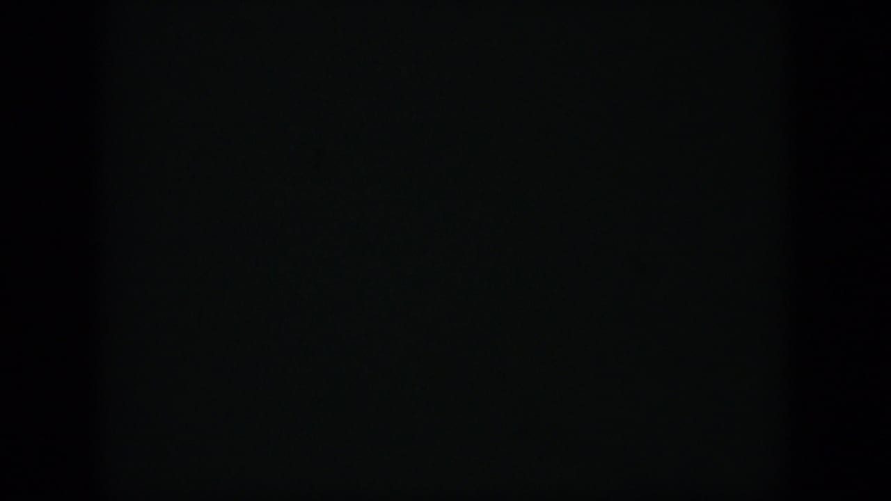 Mostly dark film frame with faint green tones and no clear subject.