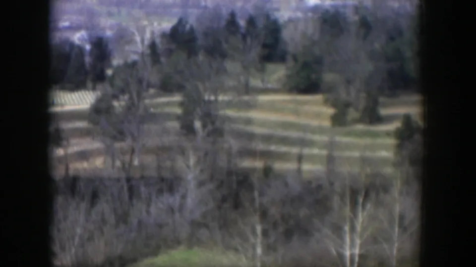 Late shot from the 1951 Cuba clip, with wooded hills, open green areas, and faint paths visible through soft 8mm focus.