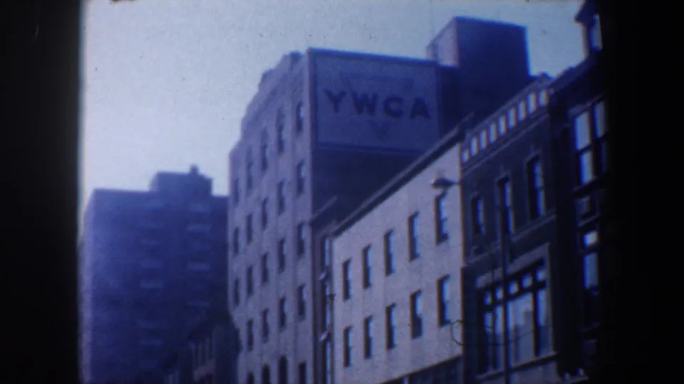 1962 Philadelphia street view from a moving vehicle, showing a multi-story YWCA building and neighboring urban facades.