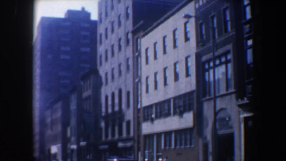 Moving-vehicle view of a Philadelphia urban block in 1962, with the YWCA building, older facades, and street-level storefronts.