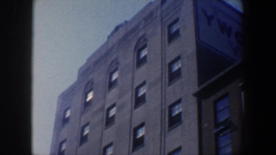 1962 Philadelphia upward angle on a multi-story building corner, showing rows of windows, a pale sky, and an adjacent darker structure.