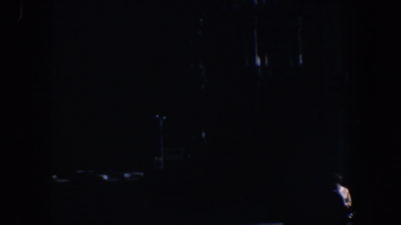 Very dark dusk frame with faint highlights and indistinct monument or architectural forms.