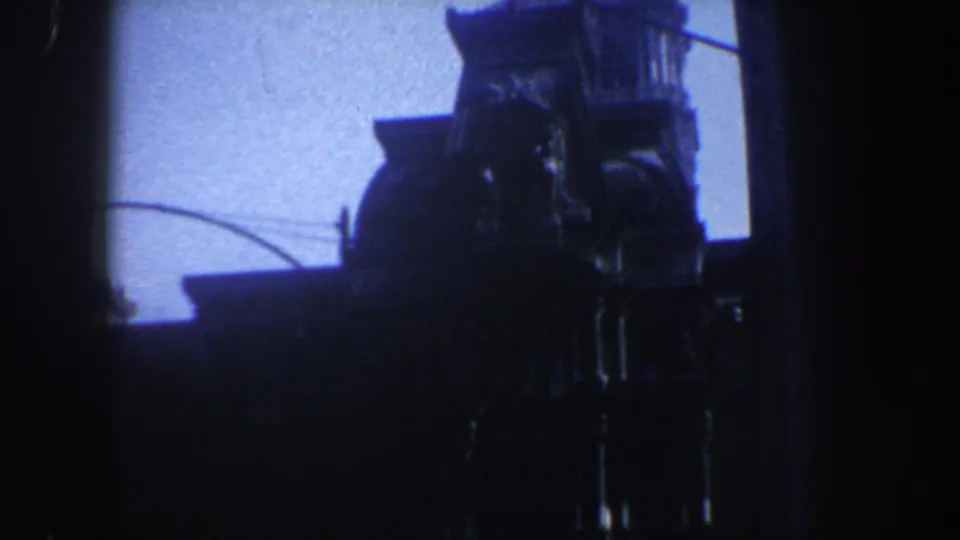 Low-light 1962 Philadelphia frame with a monument or landmark silhouette, vertical architectural forms, and blue dusk sky.