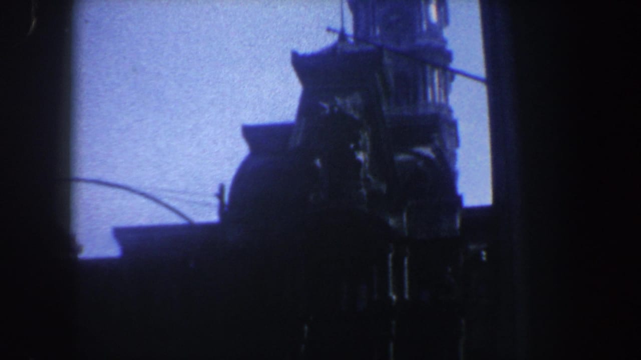Silhouetted tower top framed by dark film edges against a pale blue sky.