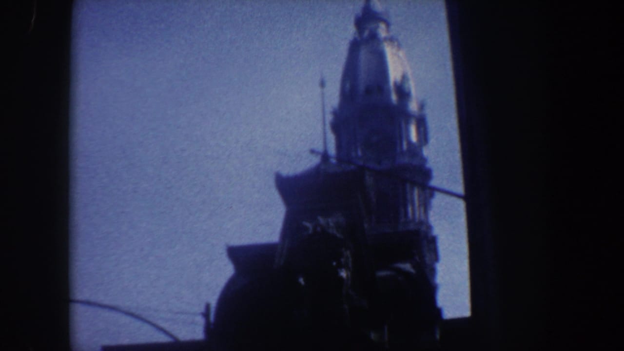 Dark church steeple silhouette against pale blue sky with film edge visible.
