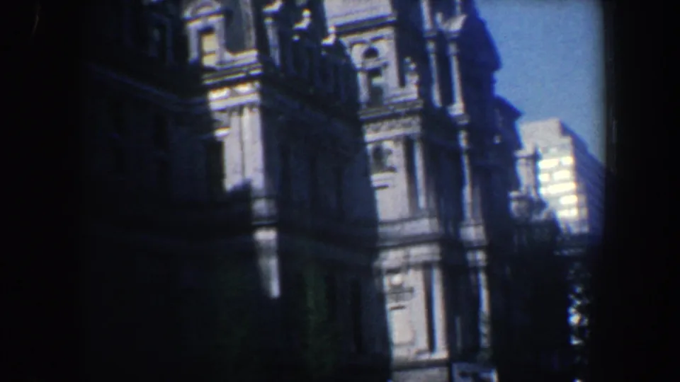 1962 Philadelphia frame with an ornate stone building dominating the foreground and sunlit high-rise structures visible beyond it.