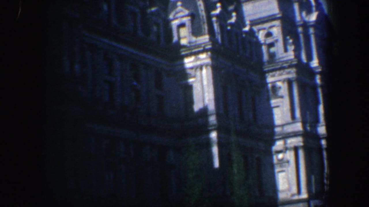 Ornate building facade in shadow with sunlit columns and upper architectural details.
