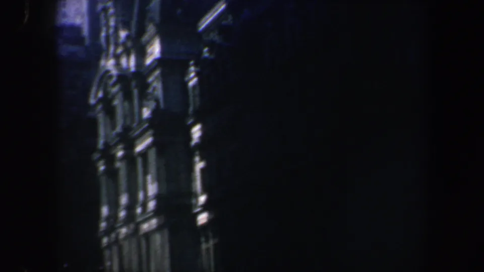 1962 Philadelphia 8mm frame showing a closer section of an ornate building facade with arched detailing, windows, and deep shadow.