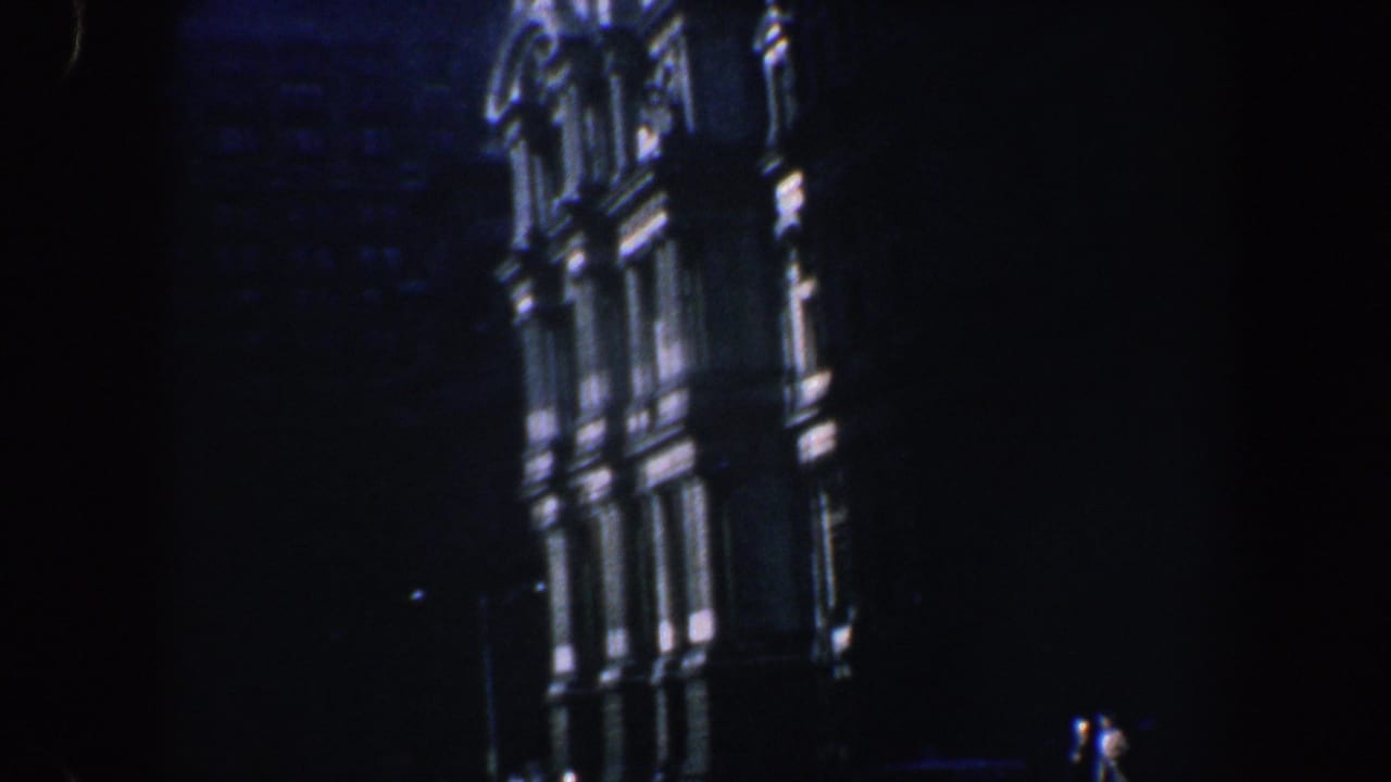 1962 Philadelphia home-movie frame showing a dark, low-angle night view of an ornate historic building facade with lit architectural edges.