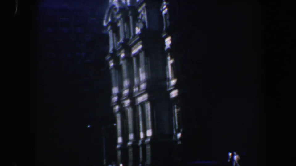 1962 Philadelphia home-movie frame showing a dark, low-angle night view of an ornate historic building facade with lit architectural edges.