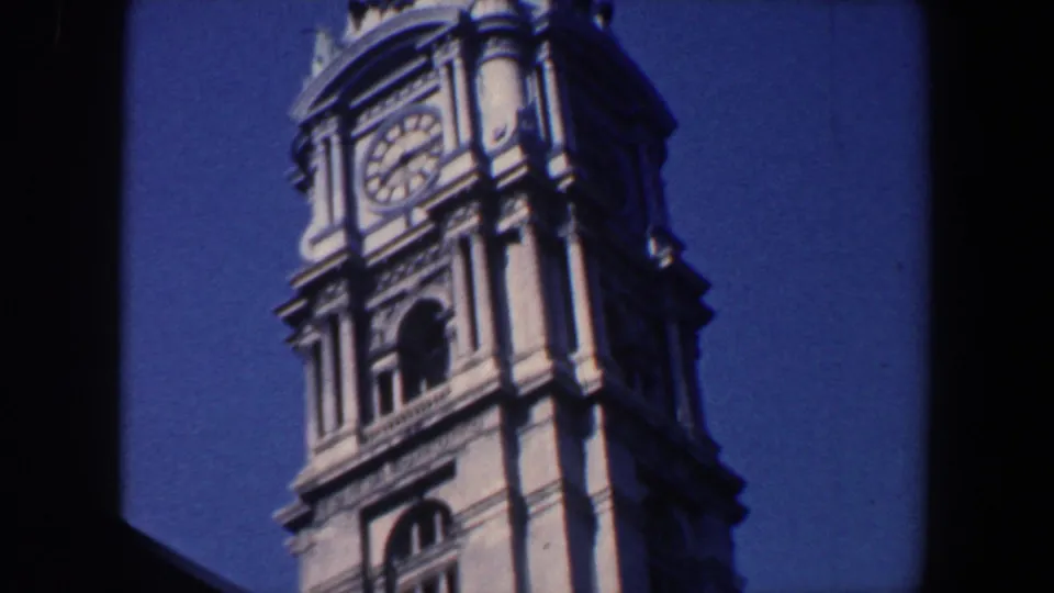 1962 Philadelphia 8mm frame showing the clock face and upper portion of an ornate stone tower viewed from below.