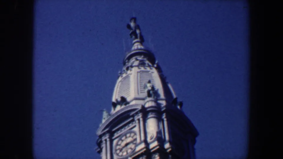 1962 Philadelphia frame showing an ornate tower top with clock face, dome details, and a small statue above it.