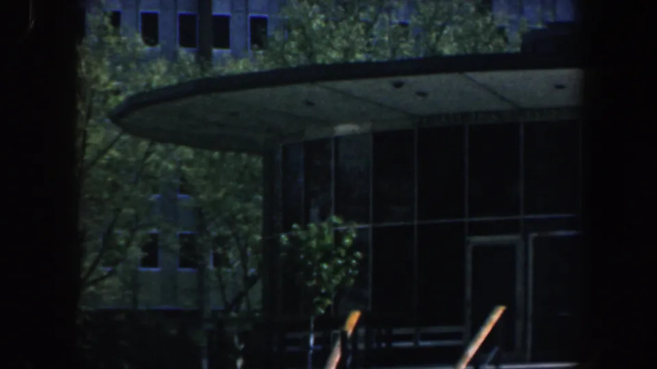 1962 Philadelphia 8mm frame showing a modern building entrance with curved canopy, glass facade, and trees in front.
