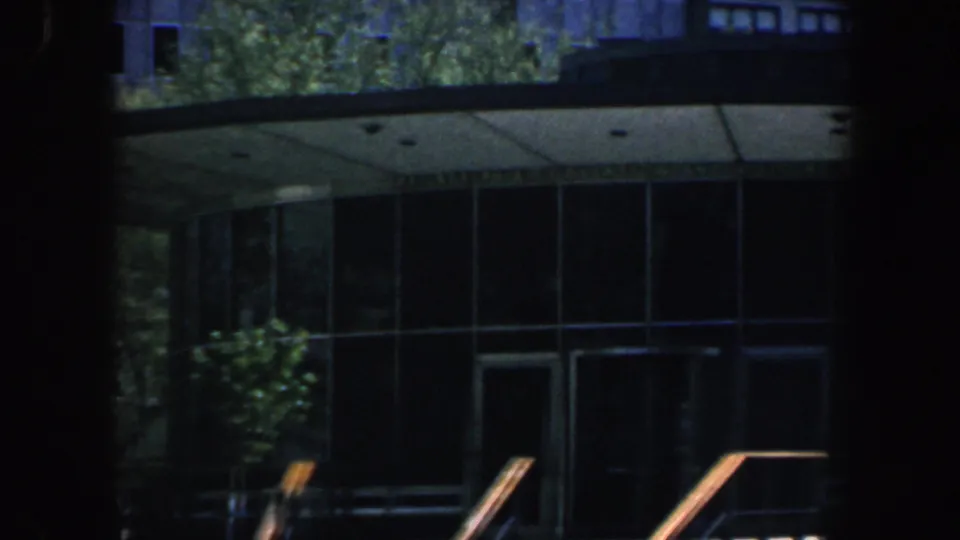 1962 Philadelphia frame of a modern building with a curved roofline, dark glass entrance, and greenery in the foreground.