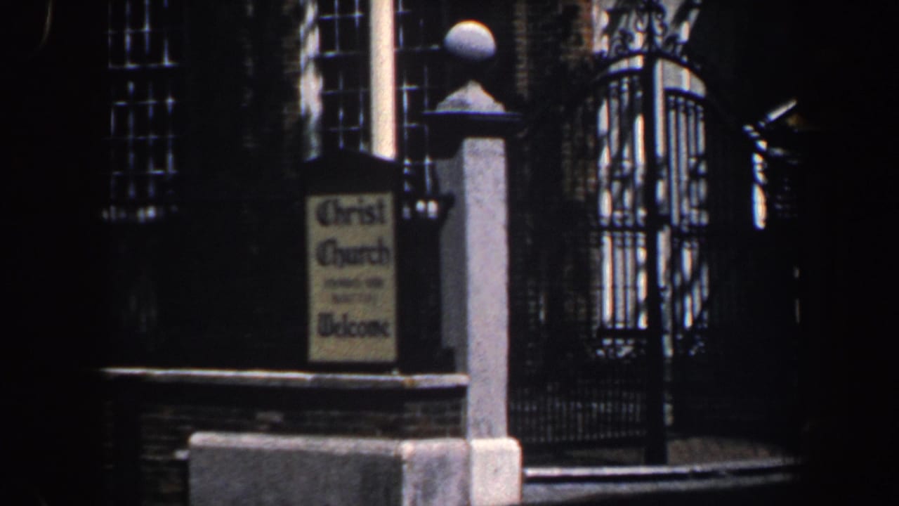 Brick church exterior with Christ Church sign, gatepost, iron gate, and tall windows.