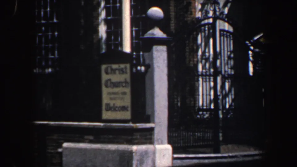 1962 Philadelphia home-movie frame showing Christ Church signage beside a wrought-iron gate and brick facade.