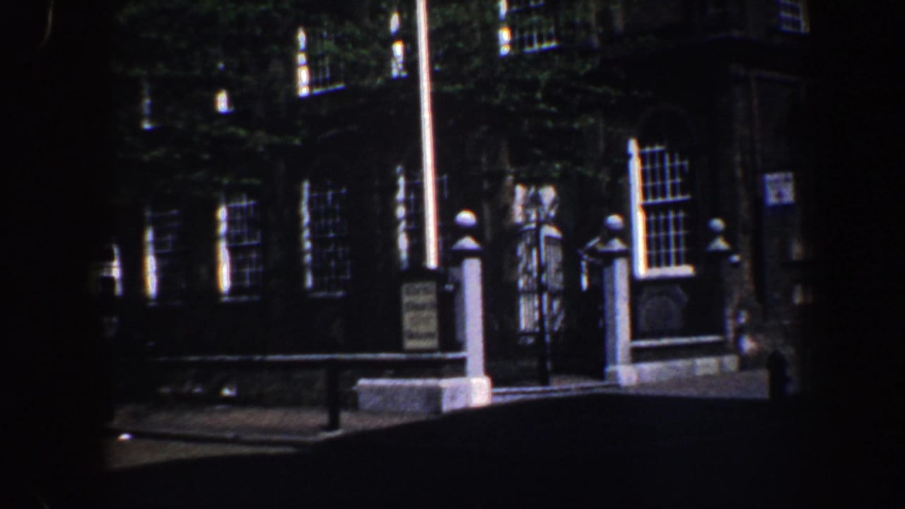 Church exterior with flagpole, gateposts, windows, ivy, and a small visitor sign.