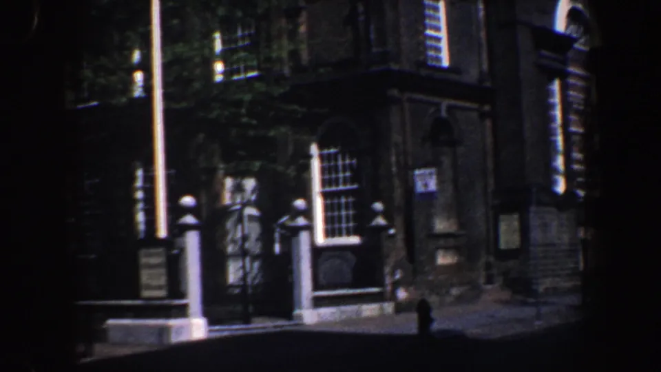 Wider 1962 Philadelphia view of the church exterior, showing the gate, flagpole, windows, signs, and doorway area.