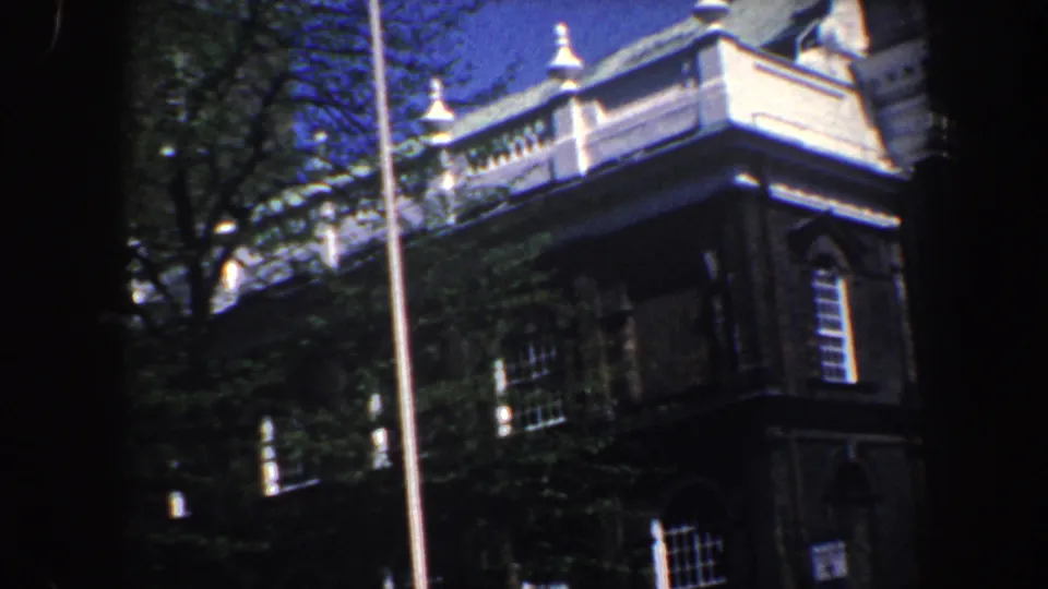 1962 Philadelphia exterior view of a brick landmark corner with white trim, gridded windows, a flagpole, trees, and blue sky.
