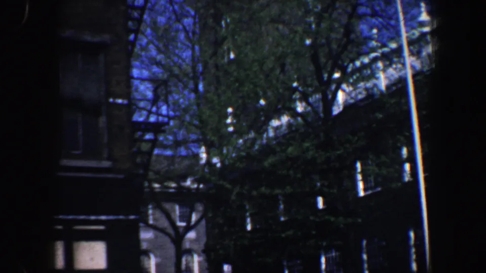 Philadelphia street exterior with brick facades, trees, fire escape details, and a pale tower partly visible through branches.